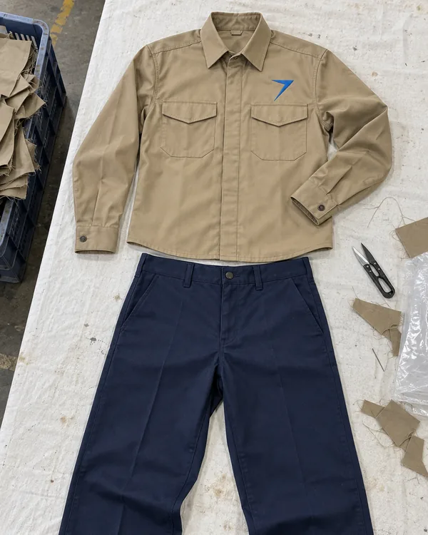 The GANTRY khaki work shirt laid flat above dark navy work pants, with a blue bolt above the left pocket