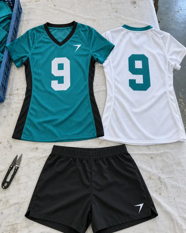 The HUDDLE kit laid flat: a teal jersey with a white 9, a white away jersey with a teal 9, and black shorts