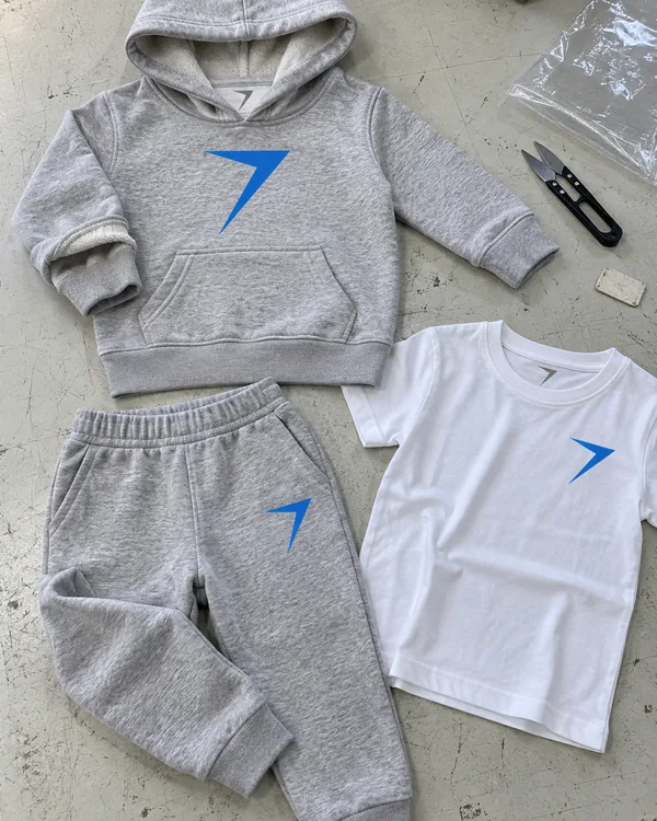 The SCOUT kids set laid flat: a gray hoodie with a plain hood edge, gray joggers and a white tee, each with a blue bolt