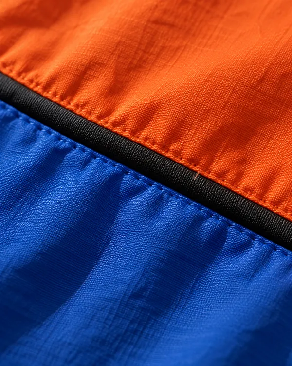 Orange and blue nylon panels joined by a black seam, close up