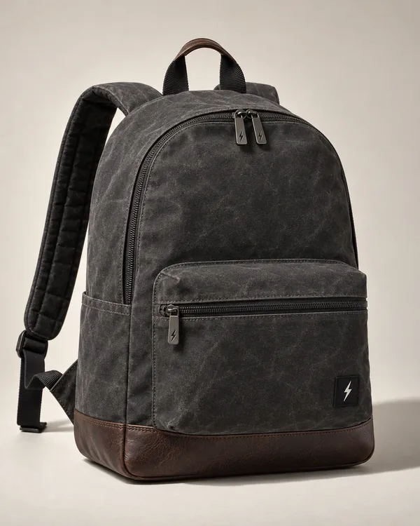 Charcoal waxed canvas backpack with a brown leather base and a small woven label