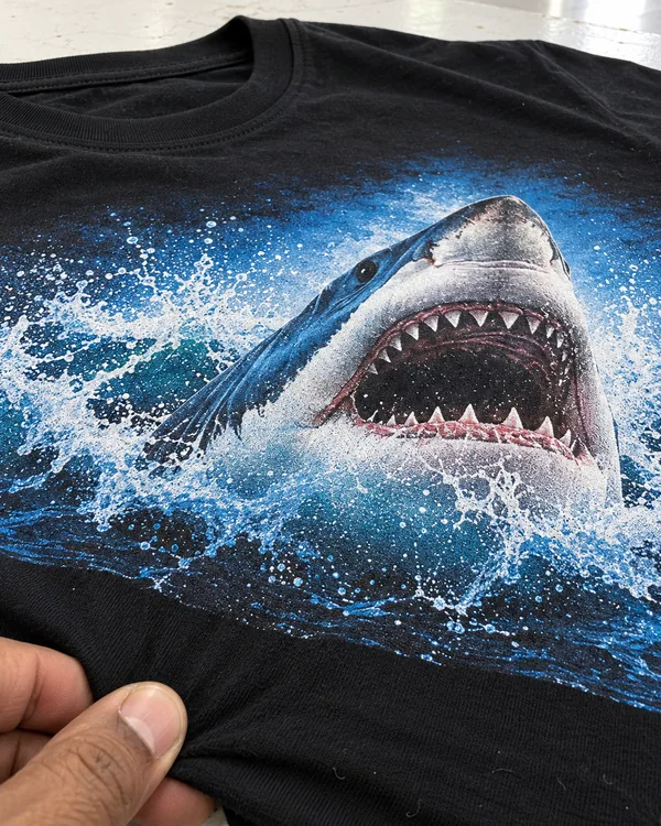 Close up of a full-color shark print on a black cotton tee, with the knit showing through the ink
