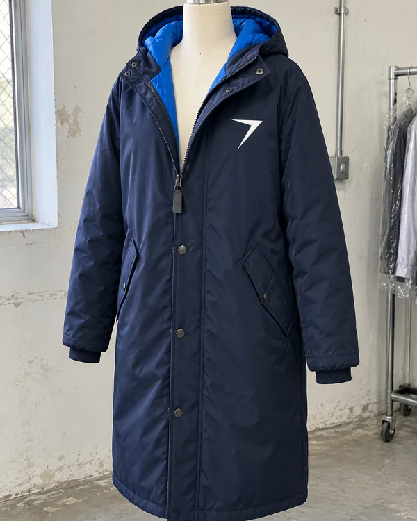 A navy knee-length sideline parka with a hood lined in blue and a white bolt on the chest, on a dress form