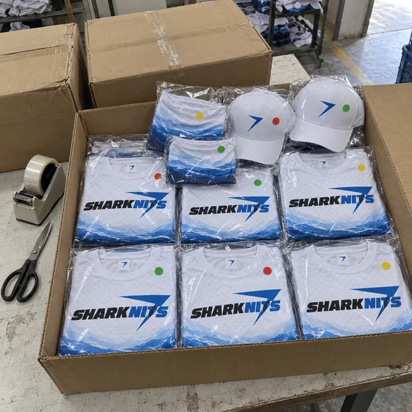 Folded TIDE jerseys in clear bags, packed in an open carton, with neck gaiters and two white caps on top