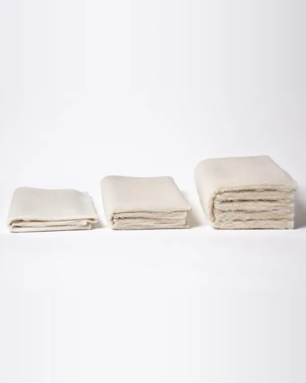 Three folded stacks of cream fabric, from thin to thick