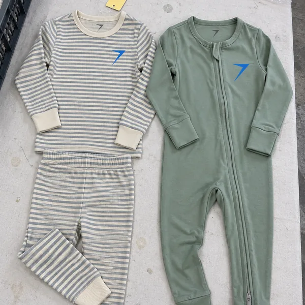 A striped snug-fitting pajama set and a sage zip sleeper with fold-over cuffs, laid flat
