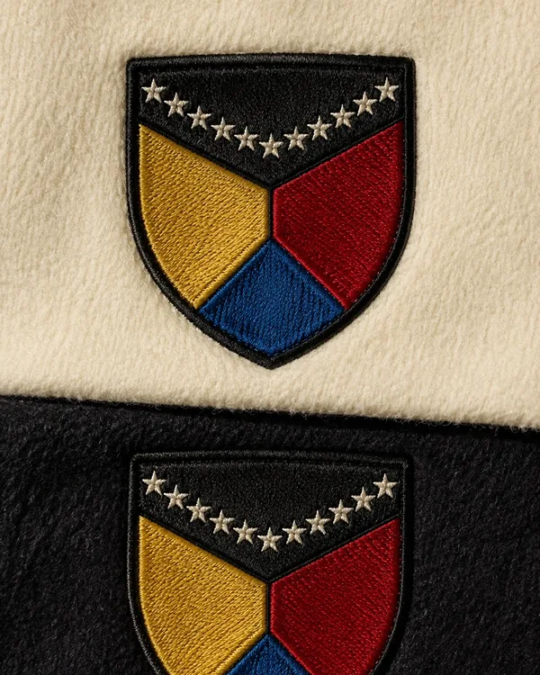 Embroidered shield patches with gold stars, on cream and black fabric