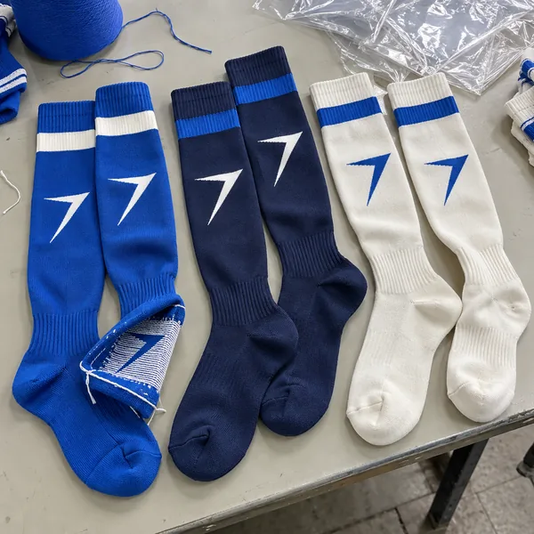 Three pairs of soccer socks in royal blue, navy and cream, each with the bolt knitted in, one sock turned inside out