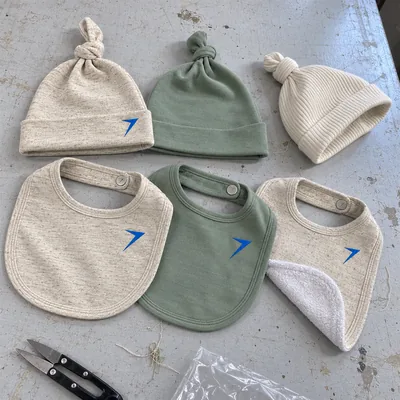 Three knot hats and three snap bibs in oatmeal, sage and cream