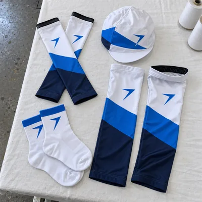 Arm and leg warmers, a white cycling cap and white socks, each with a blue bolt