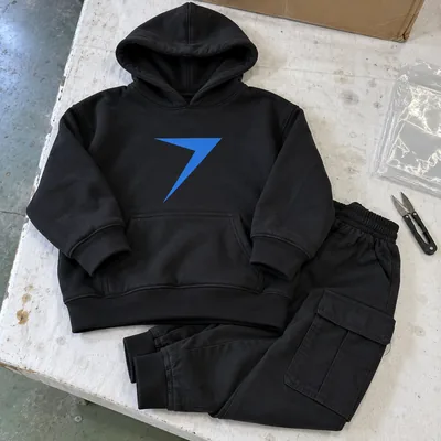 A black hoodie with a blue printed bolt and black cargo joggers, laid flat as a hip hop team set