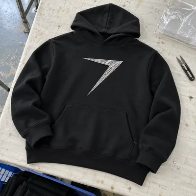 A black pullover team hoodie with a bolt in clear stones on the chest