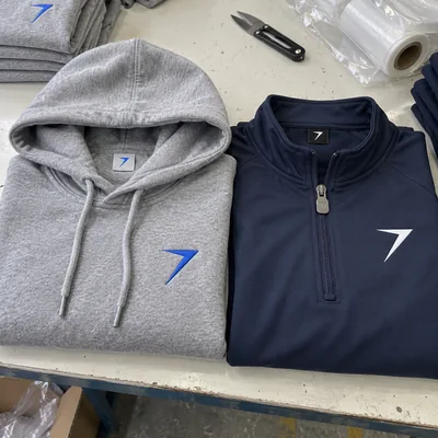 Heather gray hoodie with an embroidered blue bolt, next to a navy quarter zip with a white bolt