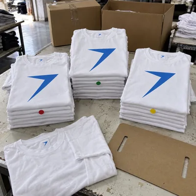 Stacks of white cotton tees screen printed with a large blue bolt