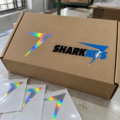 A holographic bolt sticker and a clear SHARKNITS sticker on a mailer box