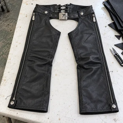Black leather riding chaps with full-length side zips, a belt and laces at the back of the waist