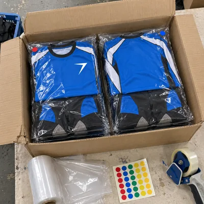 Blue motocross kits sealed in clear bags, packed in an open carton, with color dot stickers