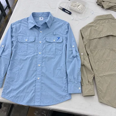 Light blue vented fishing shirt with flap pockets, next to a khaki one showing its vented back
