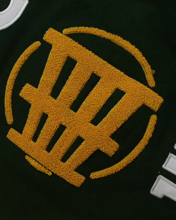 Gold chenille crest on a dark green Fince Up varsity jacket, close up