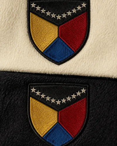 Embroidered shield patches on cream and black fabric